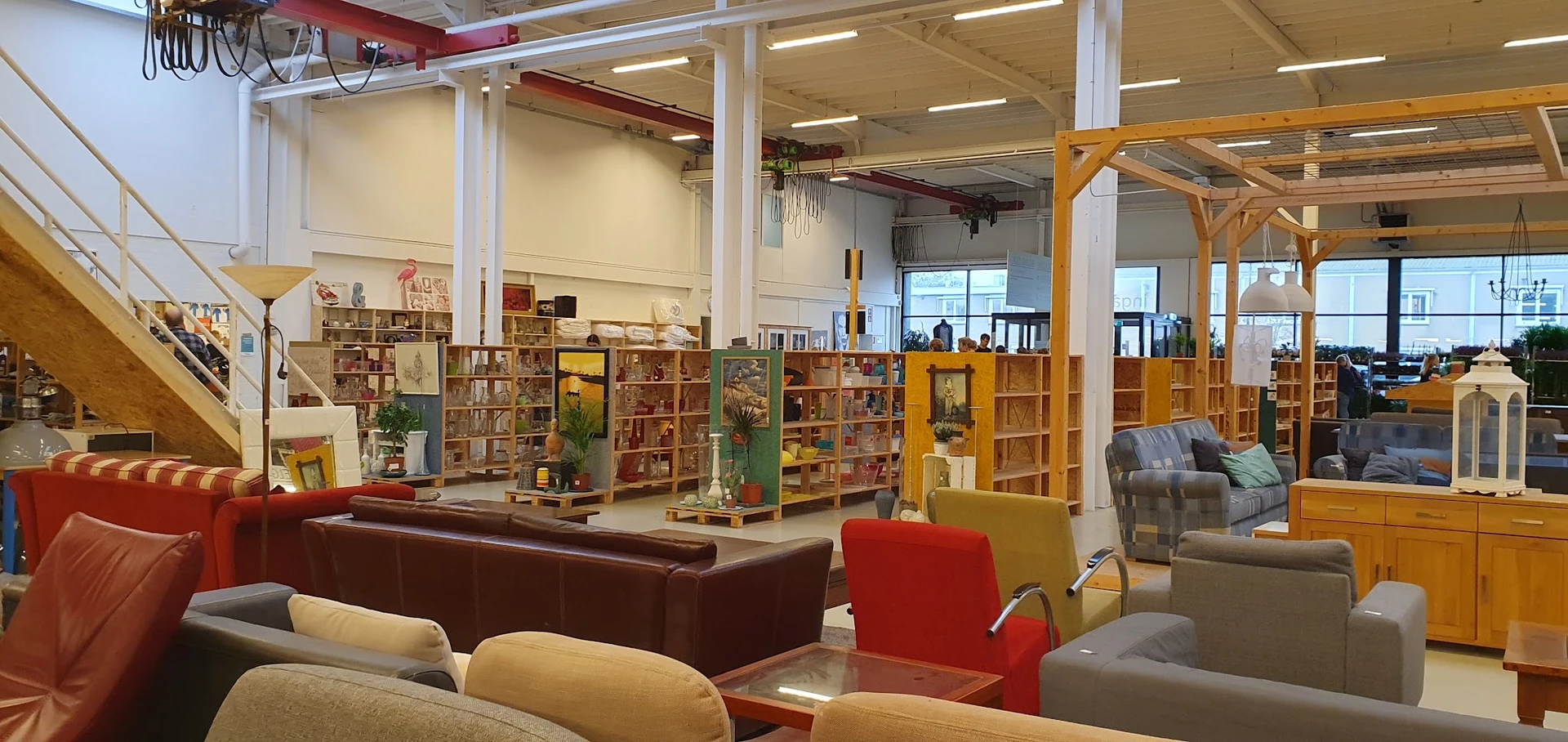 Ruim winkelinterieur met boekenrekken, zitmeubels en verschillende bruine, rode en gele kasten en stellingen