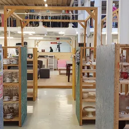 Winkelvloer met houten stellingen en vakken vol tweedehands spullen en kleding
