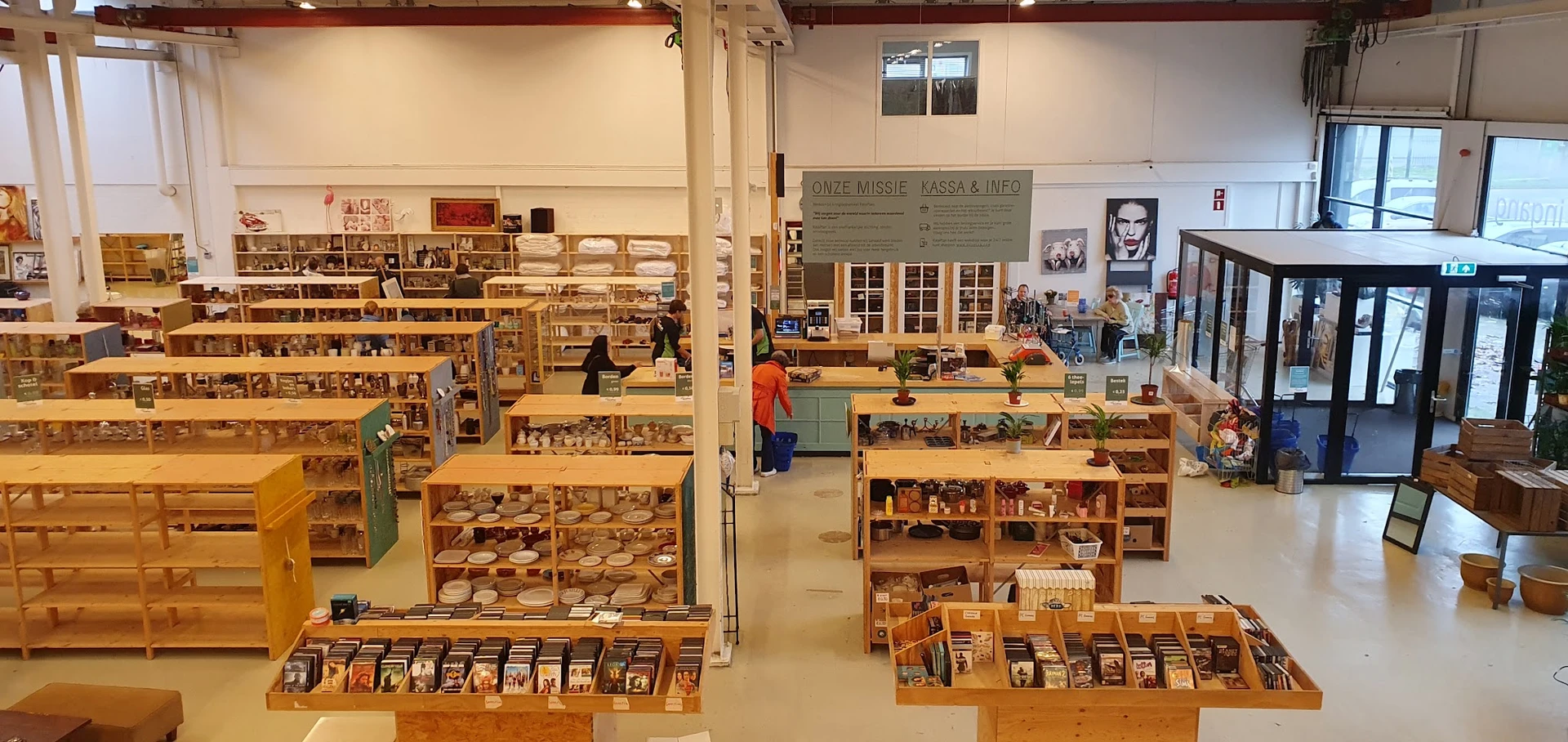 Winkelvloer van kringloopwinkel met houten stellingen vol tweedehands spullen en decoratieve items