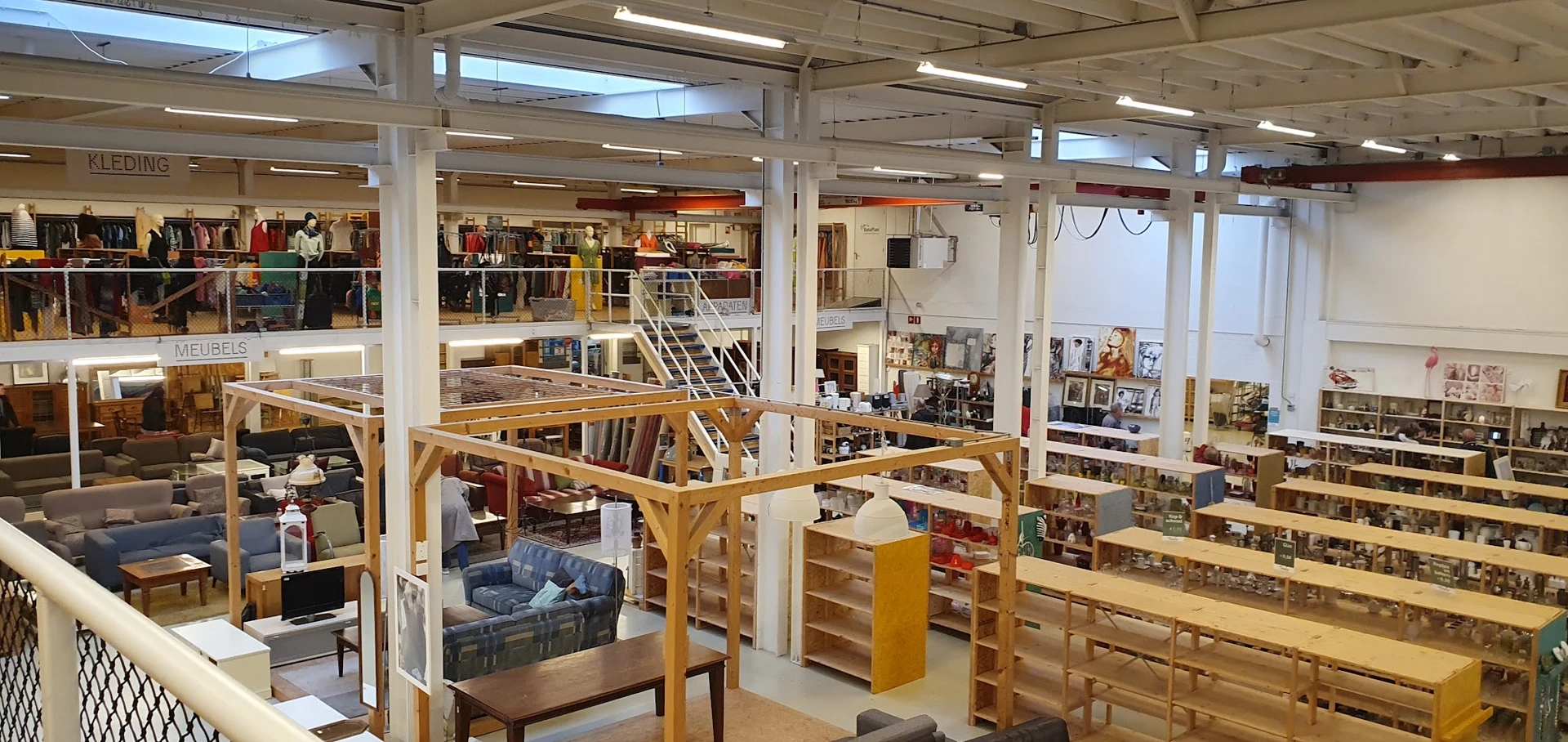Ruim winkelinterieur met houten stellingen, trappen en diverse afdelingen met tweedehands spullen