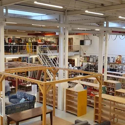 Ruim winkelinterieur met houten stellingen, trappen en diverse afdelingen met tweedehands spullen