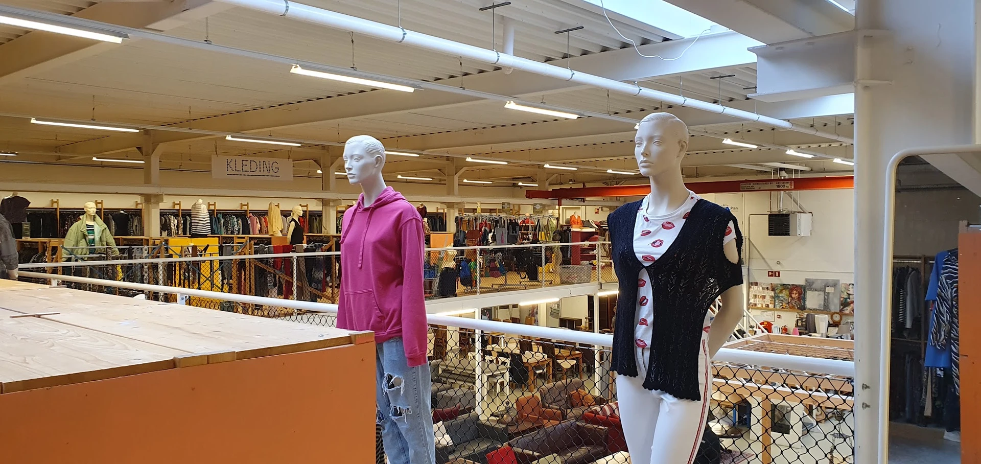 Winkelvloer met kledingrekken en twee etalagepoppen in verschillende outfits