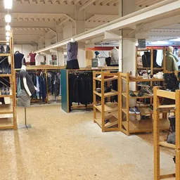 Winkelvloer met houten stellingen vol kleding, schoenen en accessoires onder LED-verlichting