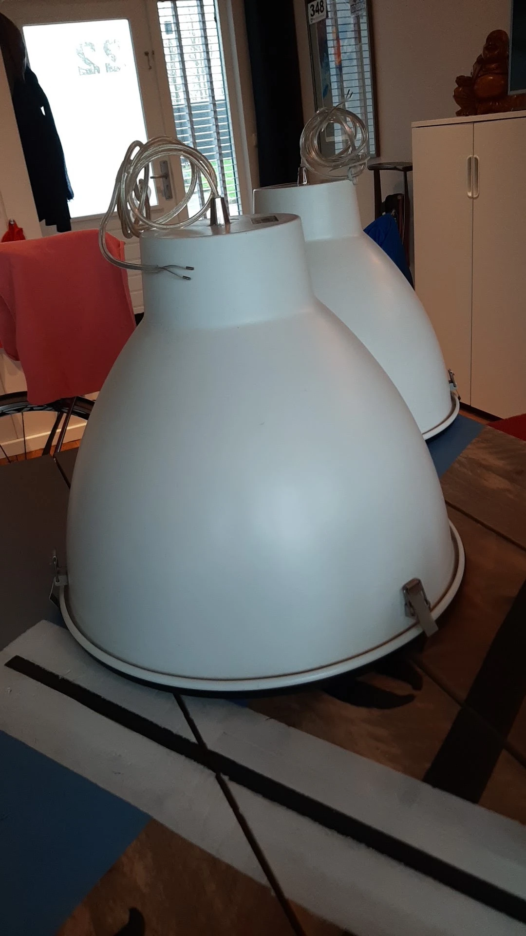 Close-up van een grote witte metalen hanglamp met afgeronde kap