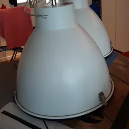 Close-up van een grote witte metalen hanglamp met afgeronde kap