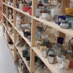 Houten stellingen met diverse huishoudelijke spullen zoals glazen, kaarsen, schalen en keramiek.