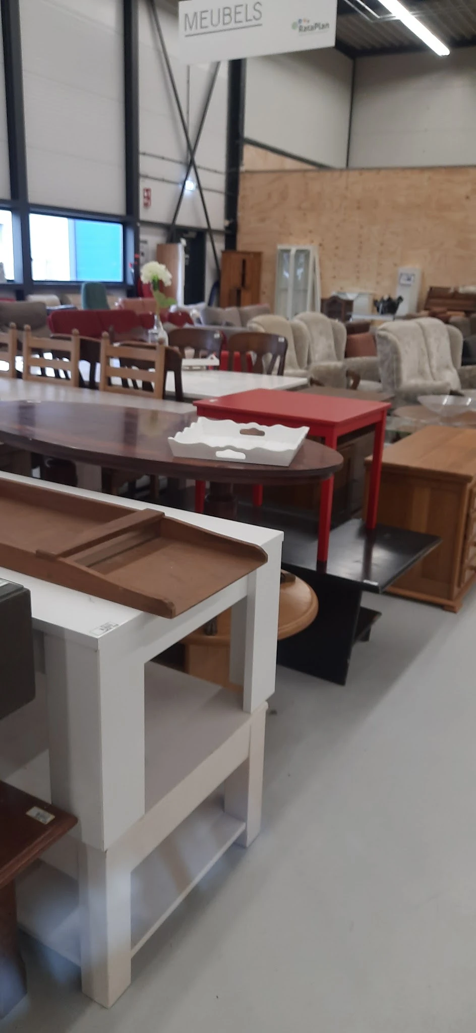 Uitgestalde meubels in verschillende kleuren en stijlen, waaronder tafels en zitmeubels