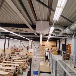 Ruim magazijn met stellingen vol kartonnen dozen en houten kasten, fluorescerende verlichting en industrieel plafond