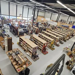 Overzicht van de winkelvloer met meerdere stellingen vol boeken en spullen, heldere verlichting van boven