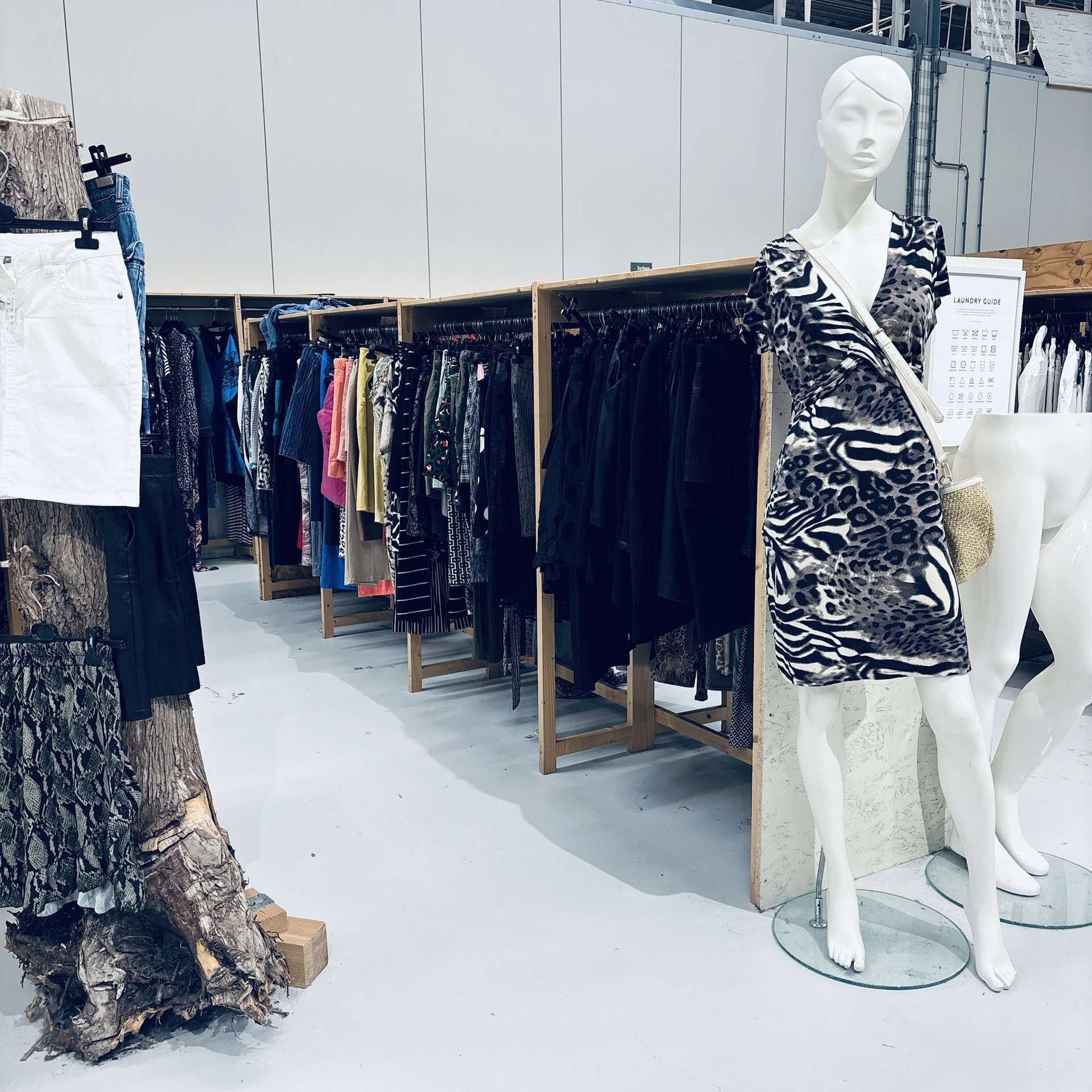 Rekken met tweedehands kleding in verschillende kleuren en stijlen, met een etalagepop in een zwart-wit dierenprint jasje