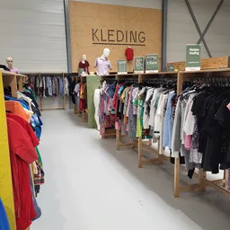 Winkelvloer met houten kledingrekken vol tweedehands kleding, uitstallingen en bord met 'KLEDING' boven