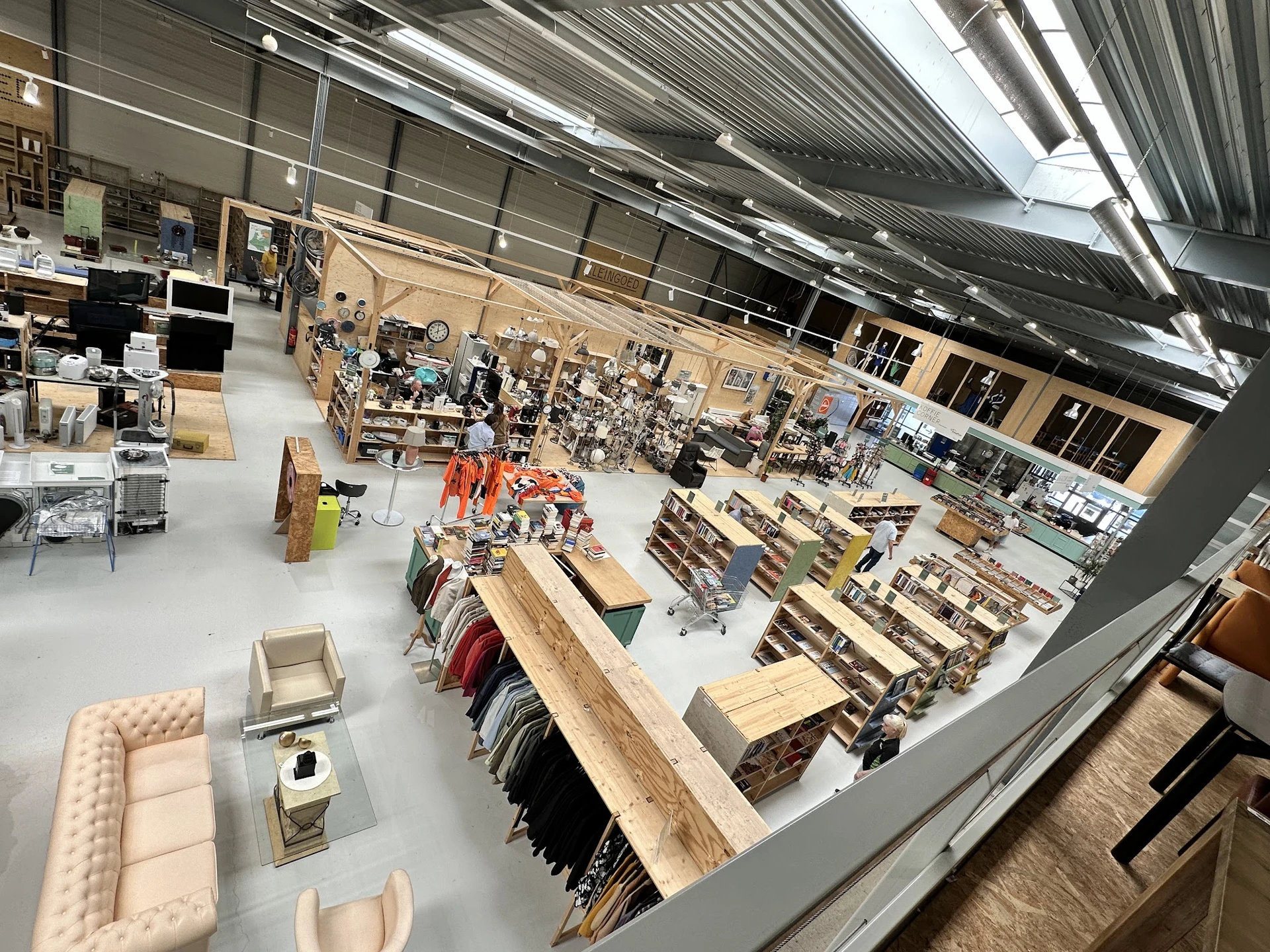 Overzicht van de winkelvloer met diverse rekken, meubels en uitgestalde artikelen onder industriële verlichting