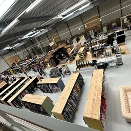 Overzicht van de winkelvloer met uitgestalde meubels, waaronder banken, houten tafels en stoelen.
