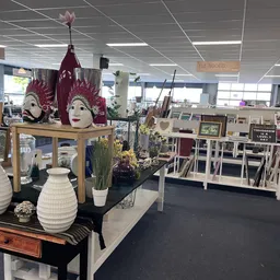 Winkelvloer met diverse decoratieve artikelen, stellingen en uitgestalde koopwaar in een ruime ruimte met plafondverlichting