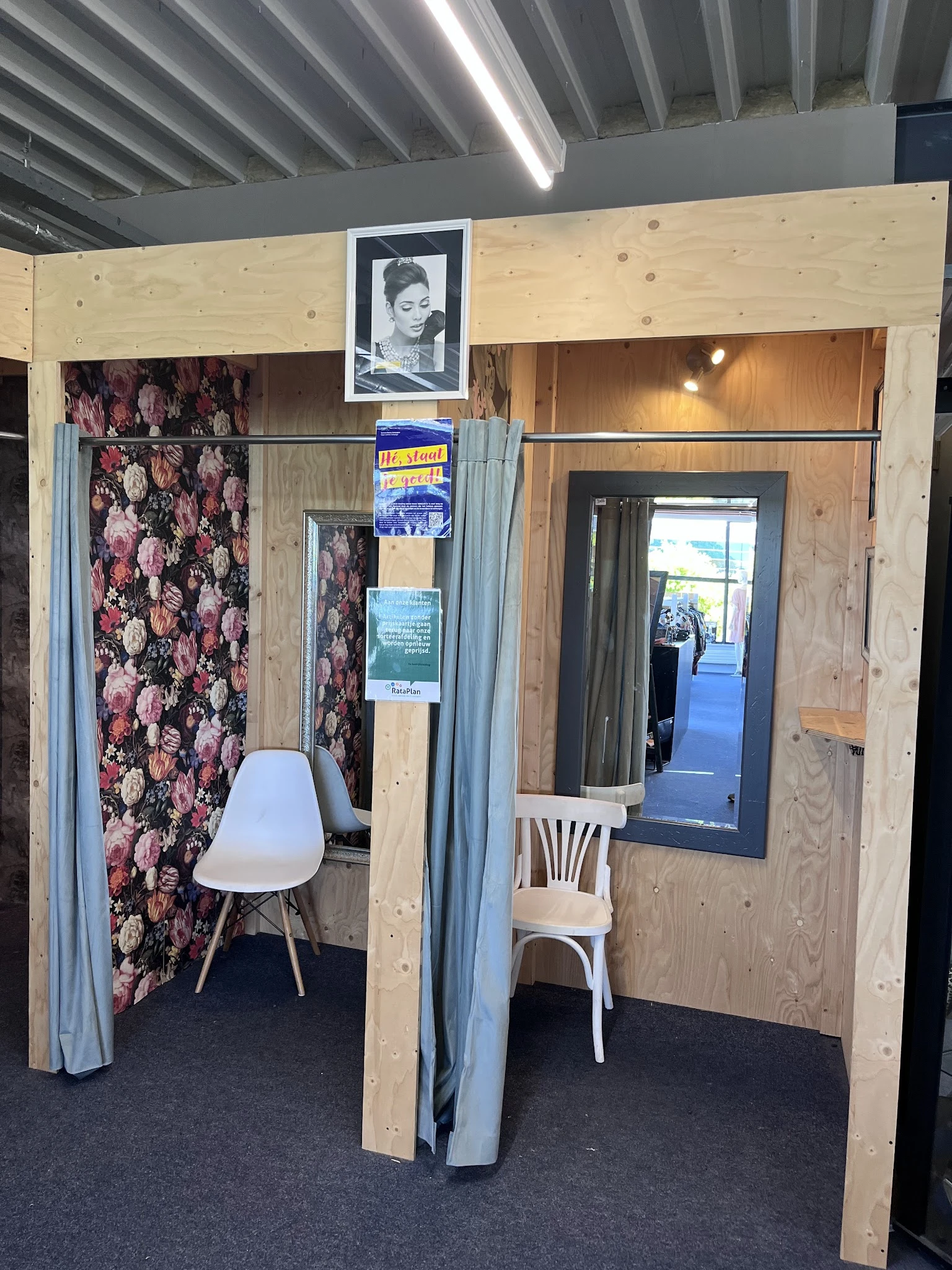 Winkelmodelopstelling met stellingwanden, bloemenpatroonbehang, stoelen en spiegels