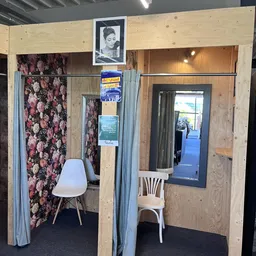 Winkelmodelopstelling met stellingwanden, bloemenpatroonbehang, stoelen en spiegels