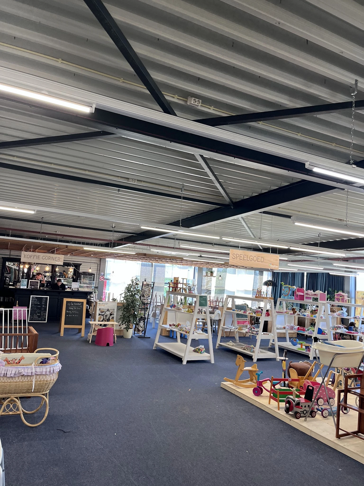 Winkelvloer van kringloopwinkel met stellingen, displays en diverse spullen, industrieel plafond met lampen