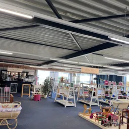 Winkelvloer van kringloopwinkel met stellingen, displays en diverse spullen, industrieel plafond met lampen