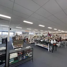 Ruim winkelinterieur met glaskasten, stellingen en hangkledij onder moderne plafondverlichting