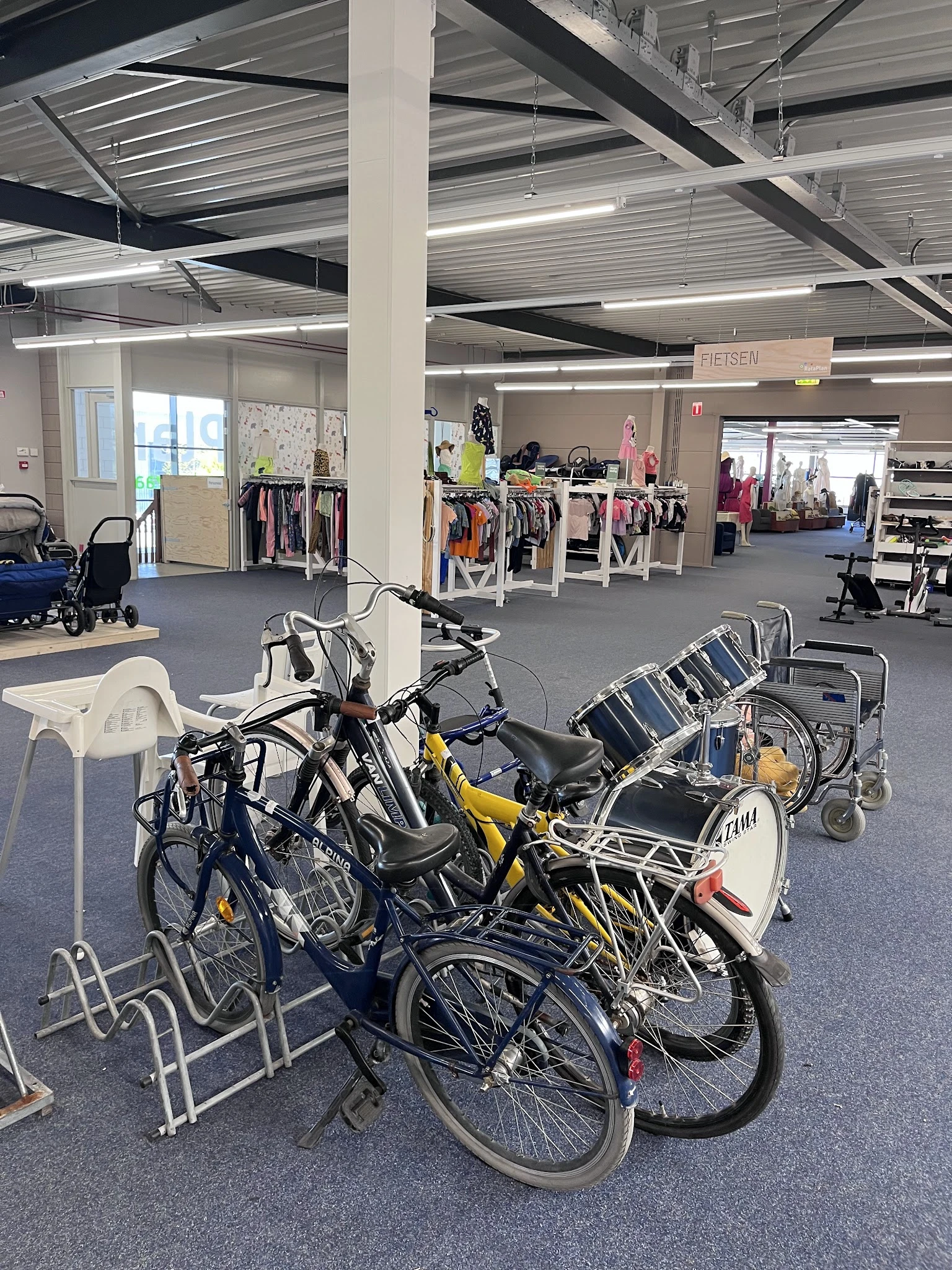 Winkelvloer met fietsen op de voorgrond en kledingrekken met dameskleding in de achtergrond