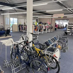 Winkelvloer met fietsen op de voorgrond en kledingrekken met dameskleding in de achtergrond