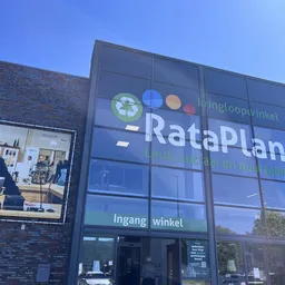 Glazen gevel van kringloopwinkel RataPlan met uithangbord en winkelramen