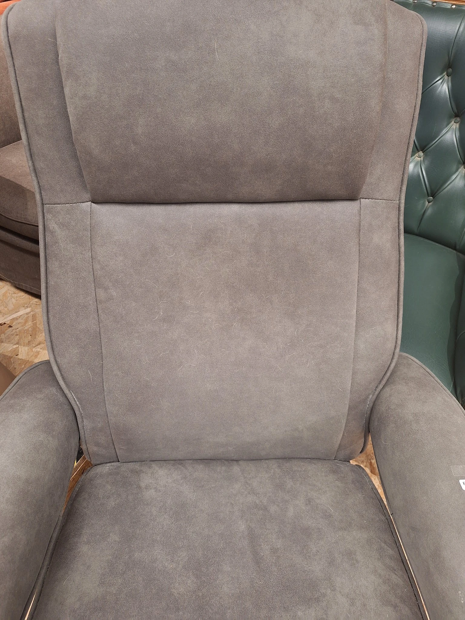 Grijze gestoffeerde fauteuil met armleuningen en houten poten, close-up van zitting en rugleuning