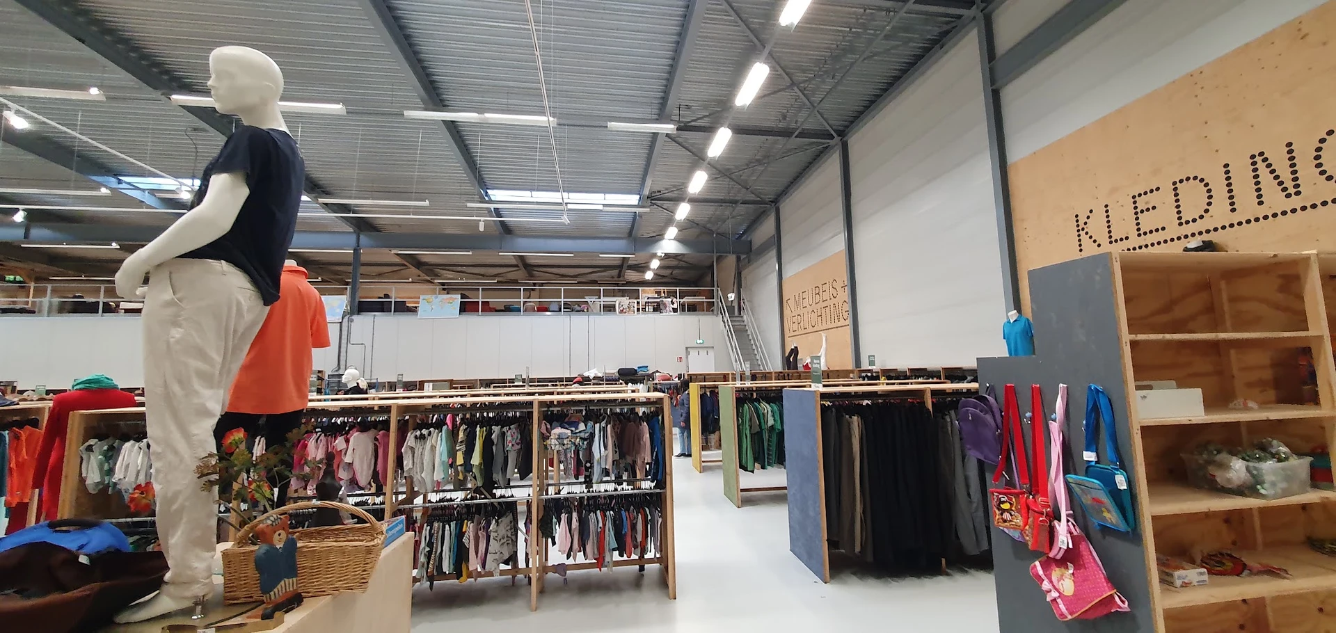 Winkelvloer met kledingrekken en stellingen met tweedehands kleding in verschillende kleuren en stijlen