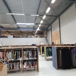 Winkelvloer met kledingrekken en stellingen met tweedehands kleding in verschillende kleuren en stijlen