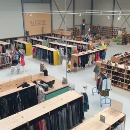 Overzicht van kringloopwinkel met kledingrekken, boekenkast en winkelafdelingen