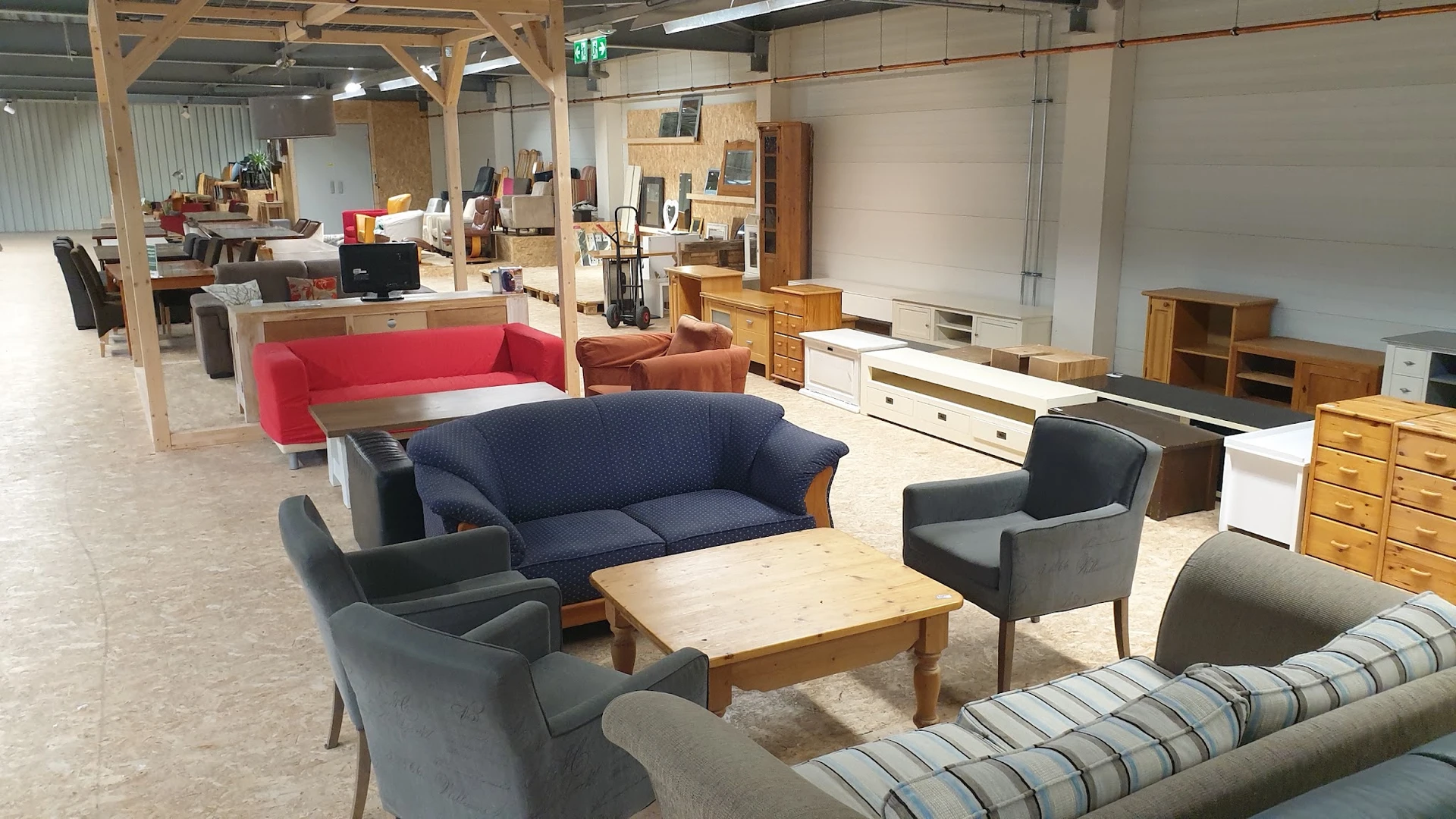 Winkelvloer met diverse meubels: blauwe en rode banken, fauteuils, houten salontafel en kasten