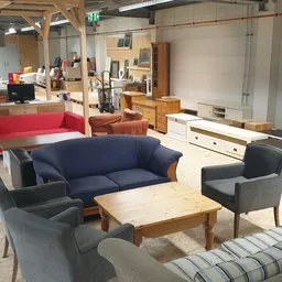 Winkelvloer met diverse meubels: blauwe en rode banken, fauteuils, houten salontafel en kasten
