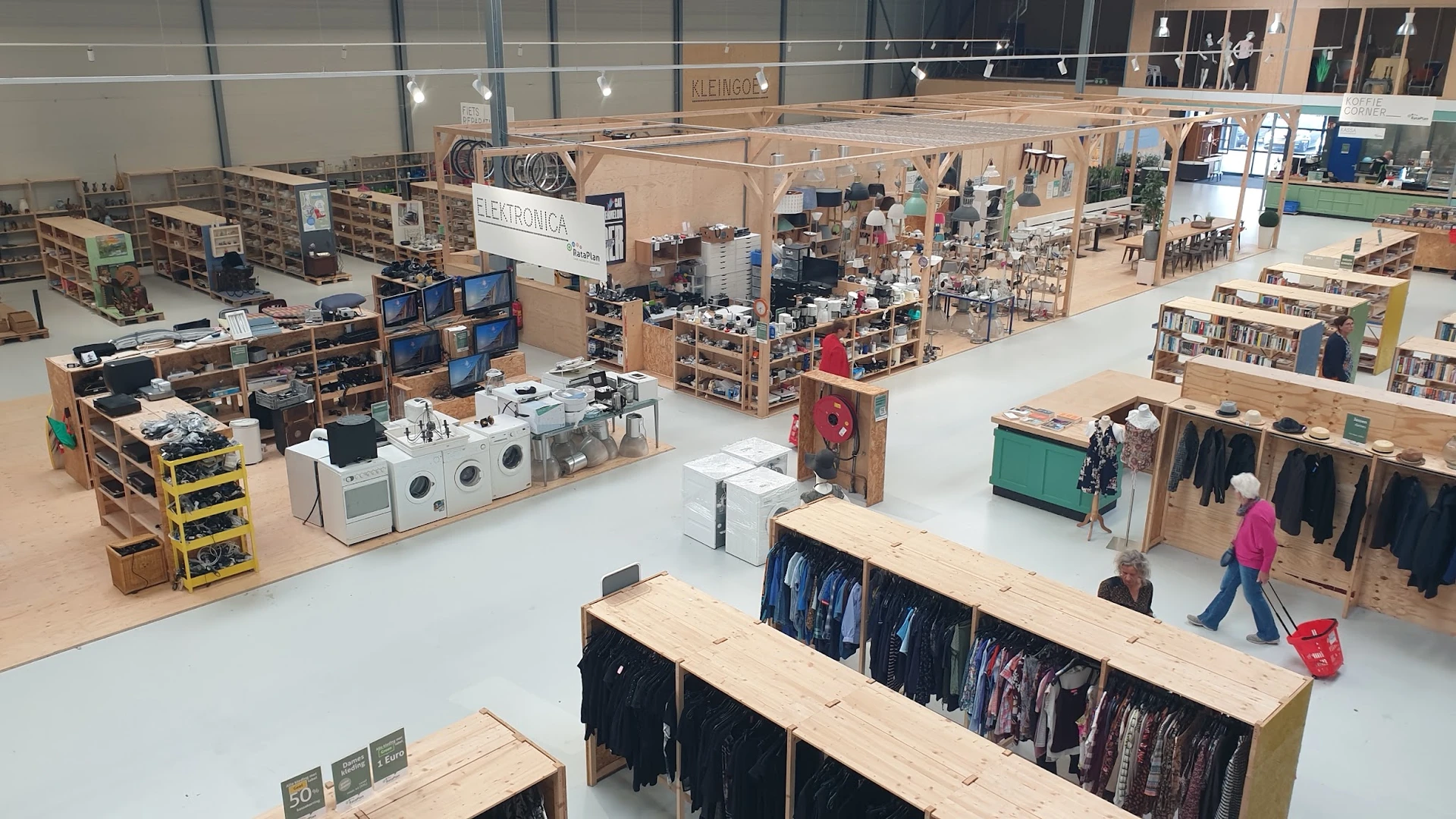 Overzicht van de kringloopwinkelvloer met rekken met kleding, huishoudelijke apparaten en diverse spullen