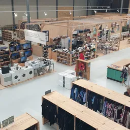 Overzicht van de kringloopwinkelvloer met rekken met kleding, huishoudelijke apparaten en diverse spullen