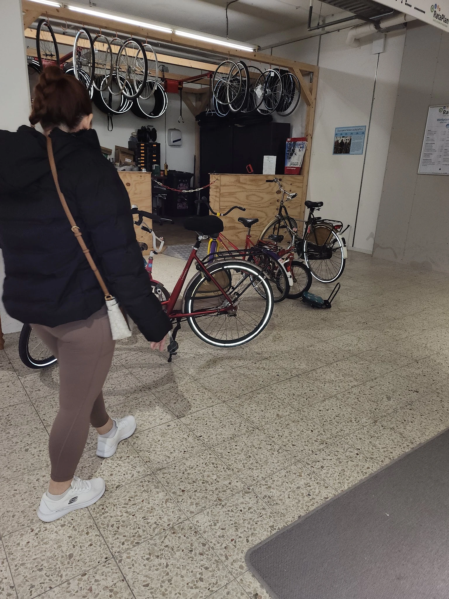 Fietsen en andere tweedehands spullen op de winkelvloer met iemand die een skateboard vasthoudt