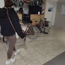 Fietsen en andere tweedehands spullen op de winkelvloer met iemand die een skateboard vasthoudt