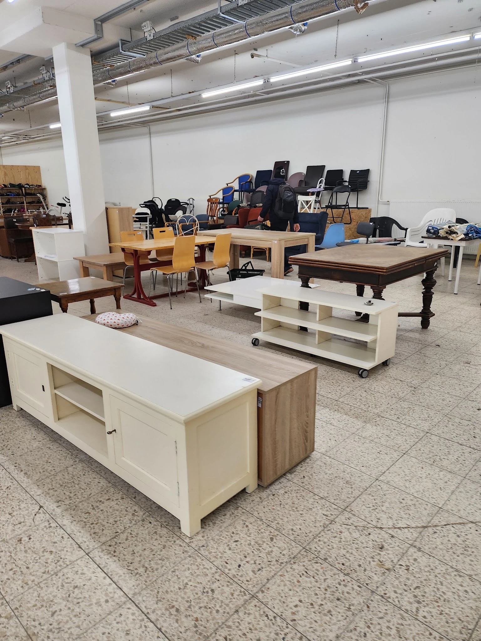 Meubels in een kringloopwinkel: kasten, tafels, stoelen en een biljart uitgestald op de vloer