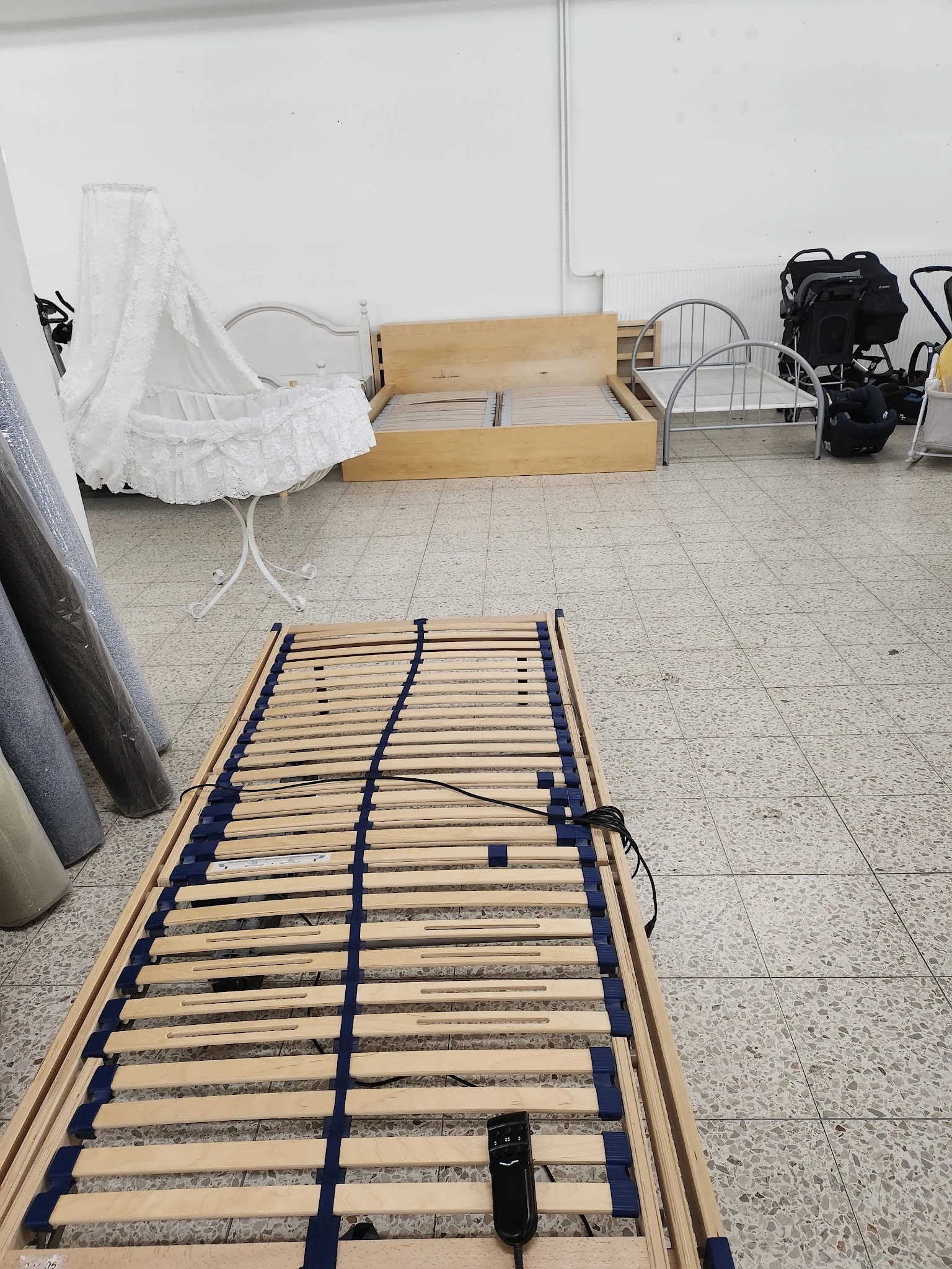 Houten lattenbodem voor bed met blauwe elastische banden, op betonnen vloer