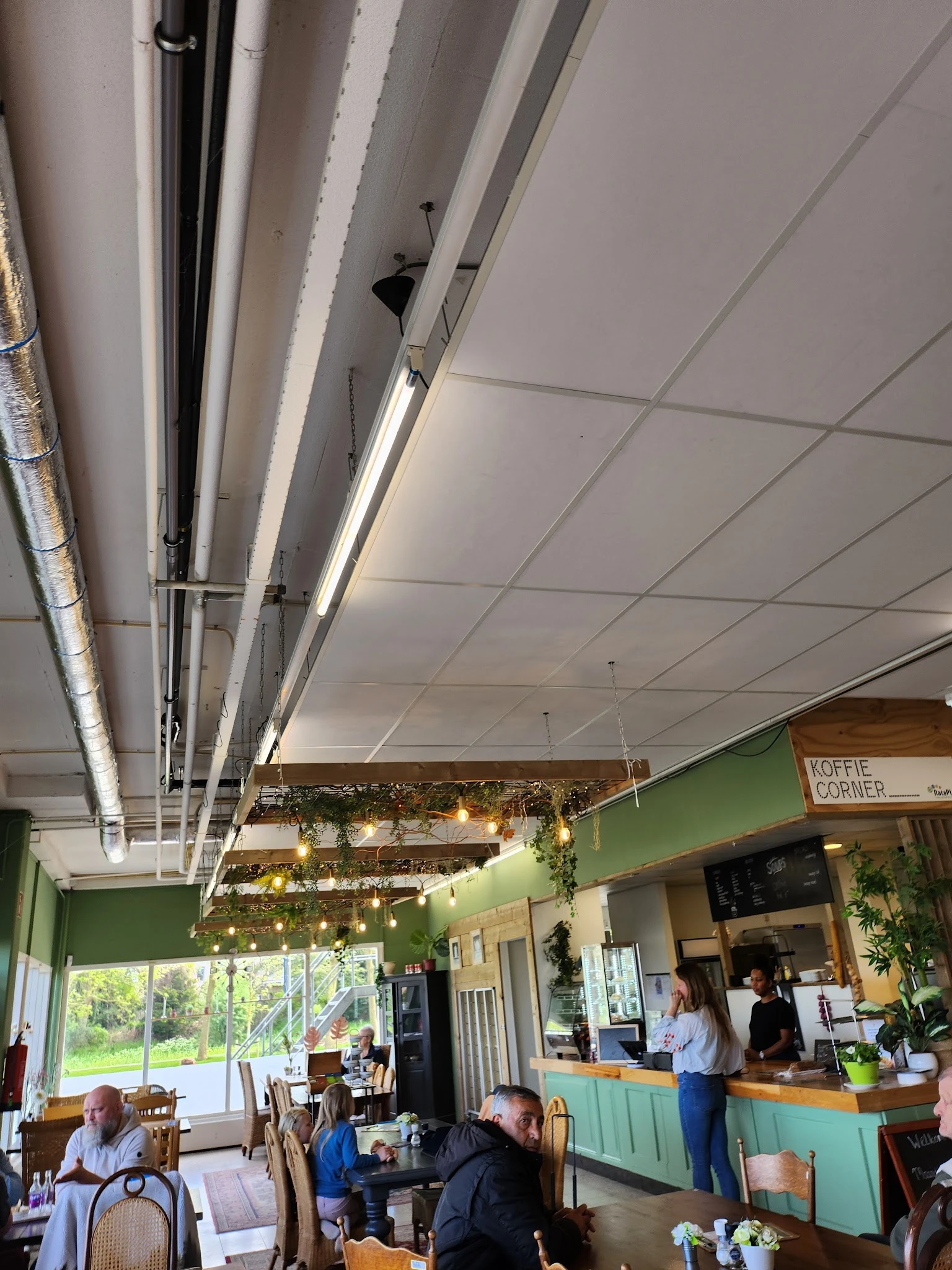 Winkelinterieur met groen geschilderde wanden, plafond met tl-verlichting en decoratieve groene guirlandes met lampjes