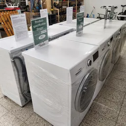Rij met witte wasmachines en droogkasten in de winkel met informatiebordje