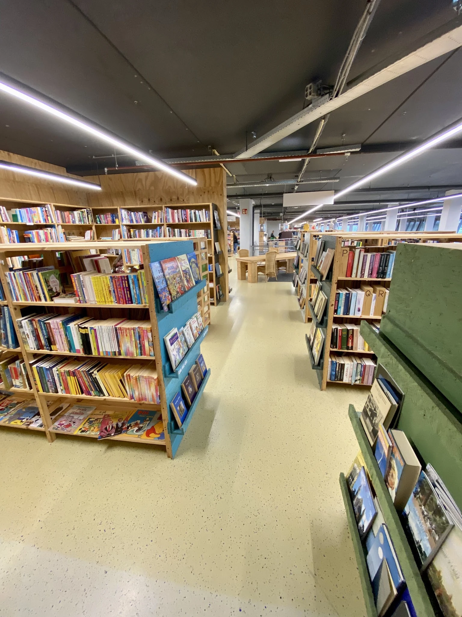 Boekenrekken met veel tweedehands boeken in een schoon, verlicht winkelinterieur