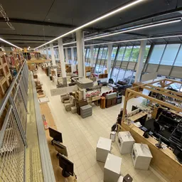 Ruim en helder winkelinterieur met stellingen, meubels en diverse tweedehandsartikelen verspreid over de vloer