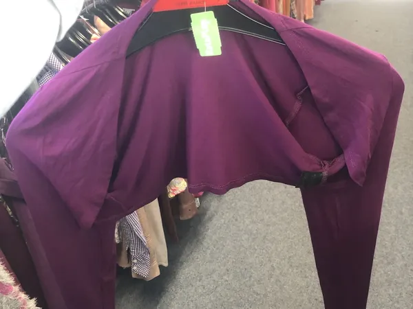 Paarse jurk op kleerhanger tegen zwarte achtergrond