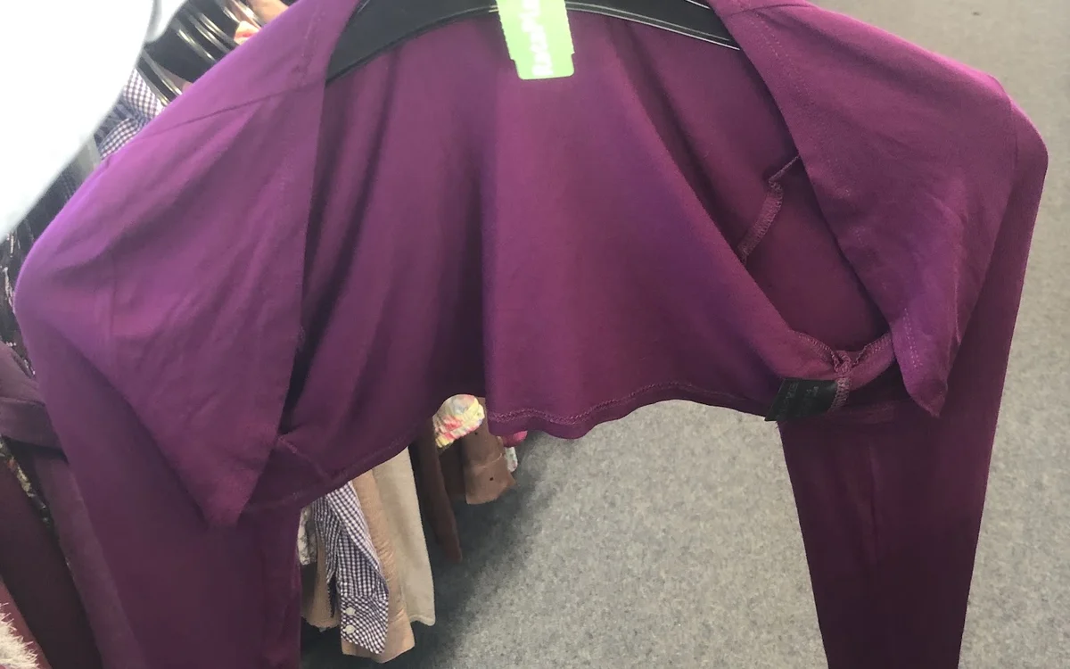 Paarse jurk op kleerhanger tegen zwarte achtergrond