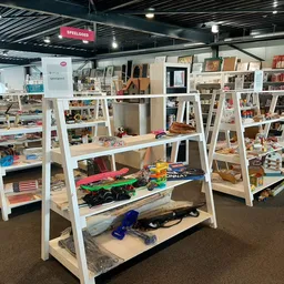 Winkelvloer met witte schappensteigers vol boeken, decoratie en huishoudartikelen