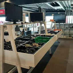 Uitgestalde elektronica en kabels in bakken op een display tafel in de kringloopwinkel