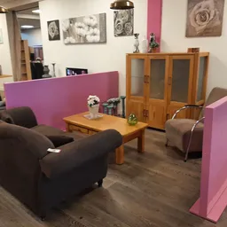 Woonkamer inrichting met bruine fauteuils, houten salontafel en roze scheidingswanden in kringloopwinkel