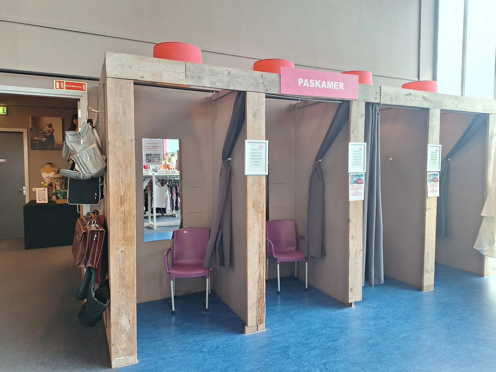 Interieur met houten boxen en paarse stoelen, blauwe vloer, rode signalering bovenaan