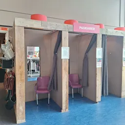 Interieur met houten boxen en paarse stoelen, blauwe vloer, rode signalering bovenaan