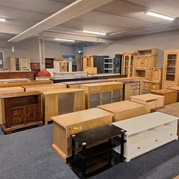 Showroom met diverse houten kasten, kastjes en meubelstukken uitgestald op grijze vloer